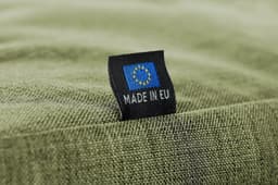 A green fabric surface with a tag featuring a logo and text indicating "MADE IN EU."