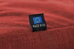 A red fabric with a small label featuring a European flag and the text "MADE IN EU."