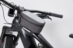 A grey bicycle frame bag sits atop a black bicycle frame, featuring a zip closure and a compact design.