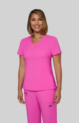 A woman wearing a bright pink top and matching pants, smiling and standing against a grey background. The outfit features a logo.