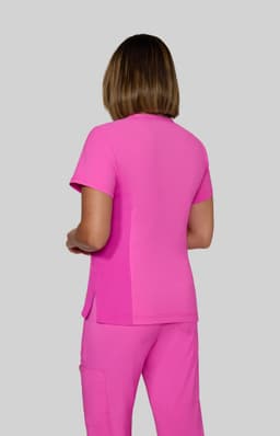 A pink top is worn by a person standing with their back to the camera, featuring short sleeves and a sleek design.
