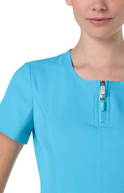 A close-up of a women's top in bright blue, featuring a zippered neckline and short sleeves. There's a logo on the fabric.