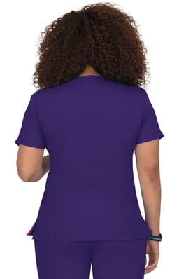 A woman wearing a purple top with short sleeves is seen from behind. The garment has a logo.