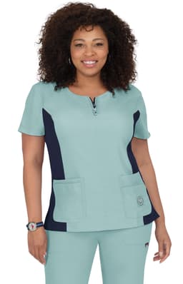 A short-sleeved scrub top in teal with navy side panels and two front pockets. Features a logo on the left side.