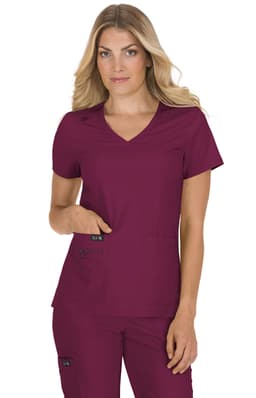 A woman is wearing a burgundy scrub top with a v-neck and pockets. The top features a logo.