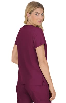 A woman models a burgundy top with short sleeves, showing a back view. The top features a logo and a relaxed fit.