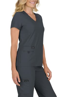 A woman wearing a charcoal grey scrub top with a V-neck and short sleeves, featuring two front pockets.