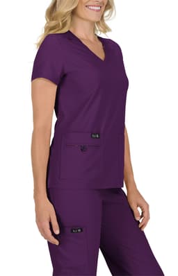 A woman wearing a purple medical scrub top with a v-neck and two front pockets, accompanied by matching pants.