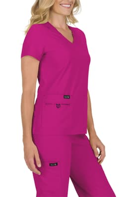 A woman wearing a vibrant fuchsia scrub top and matching pants, featuring pockets and branding.