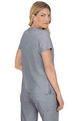 A woman wearing a grey medical top with short sleeves and a relaxed fit, featuring a subtle logo.