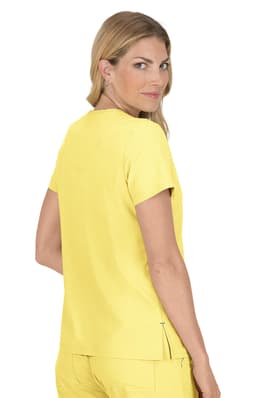 A woman models a bright yellow top, standing with her back to the camera and looking over her shoulder. The top has a logo.