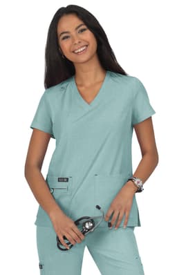 A woman wearing a teal scrub top, posing with a stethoscope. The top features two pockets and branding on the left side.