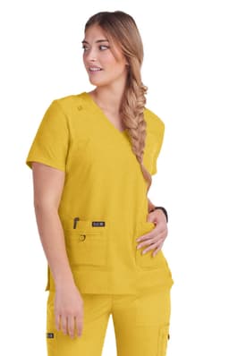 A woman wears a vibrant yellow scrub top with a v-neck and pockets, featuring a logo.
