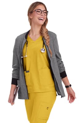 A woman wearing a grey jacket over a yellow top and pants, with a stethoscope around her neck.