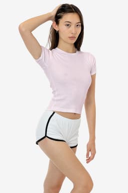A light pink baby rib tee paired with white shorts featuring black trim, displayed on a model in a neutral setting.