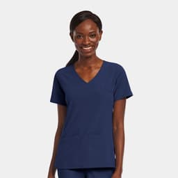 A woman wearing a navy blue mock wrap top with a V-neck and two front pockets. The top features a logo.