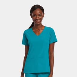 A mock wrap top in teal worn by a smiling woman, featuring two front pockets and a v-neck design.
