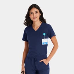 A navy v-neck top designed for women, featuring a tuckable design and a badge holder. The model has long dark hair.