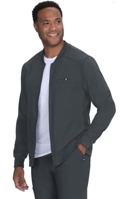 A man in a dark grey jacket with a zip, smiling and wearing a white t-shirt underneath. The jacket features a logo.