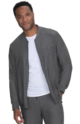A man wears a grey jacket over a white shirt, featuring a zip pocket and a casual style. The jacket has a logo.