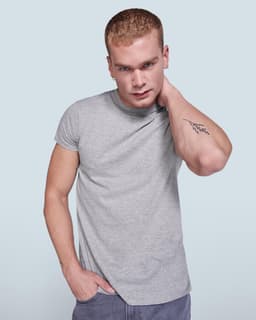 A grey T-shirt on a model with short hair, featuring a logo and casual fit.