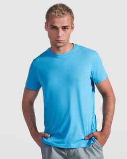 A blue t-shirt with a round neck, worn by a model posing with hands on his hips. The shirt has a logo.