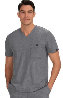 A grey V-neck scrub top featuring a chest pocket and a logo. The model is casually posing with hands in pockets.