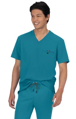 A teal scrubs top featuring a v-neck design and a pocket, modelled by a smiling person.