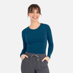 A fitted long-sleeve tee in deep teal, paired with grey drawstring pants. The tee features a logo on one sleeve.