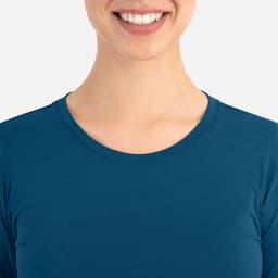 A close-up of a smiling person wearing a teal women's underscrub tee with a round neckline.