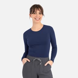 A navy long-sleeve women's underscrub tee with a fitted design, paired with grey trousers.