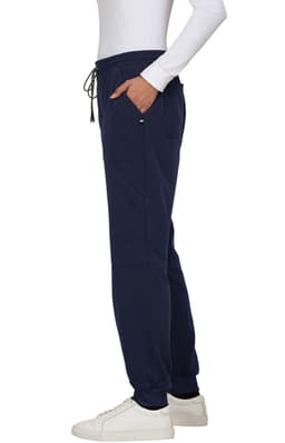 A pair of navy jogger pants with pockets and a drawstring waist, worn with a white long-sleeve top and white shoes.