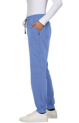 A pair of blue jogger pants with pockets and a drawstring, worn with white shoes. Features a small logo.