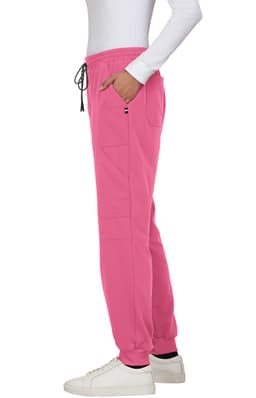 A pair of pink jogger pants with pockets and a drawstring waist, worn with white sneakers. Features branding.