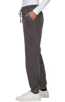 A pair of dark grey jogger pants with an elastic waistband and side pocket, worn with a white long-sleeve top and white shoes.