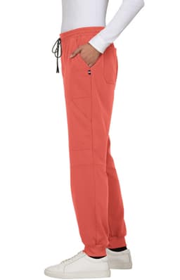 A pair of coral jogger pants with side pockets, featuring an elastic waistband and a drawstring, styled with a white top.