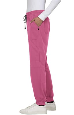A pair of pink jogger pants with a drawstring waist and pockets, worn with a white long-sleeve top and shoes.
