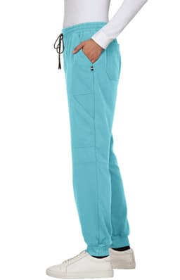 A side view of teal jogger pants with pockets, paired with a white top and white sneakers, featuring a logo.