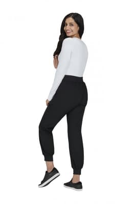 A woman in a white top and black joggers poses from the back, showcasing the Hettie Jogger style.