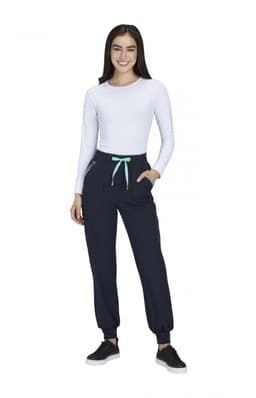 A woman in a white long-sleeve top and navy joggers with a mint green drawstring and pockets. The joggers have branding.
