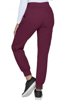 A pair of burgundy joggers with pockets and elastic cuffs, worn with a white long-sleeve top and black sneakers.