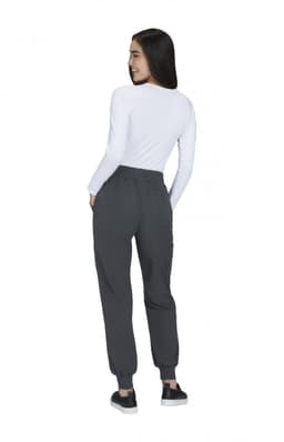 A woman is wearing grey joggers and a white long-sleeve top, facing away with a logo on the joggers.