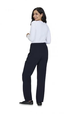 A woman stands with her back to the camera, wearing navy wide-leg pants and a white long-sleeve top.
