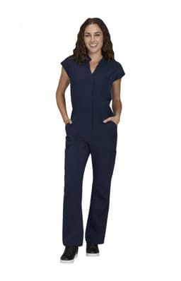A woman wearing a navy jumpsuit with short sleeves and pockets, standing confidently. The outfit has a subtle logo.