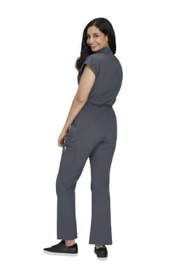 A grey jumpsuit with short sleeves and a cinched waist, worn by a woman. It features pockets and black shoes.