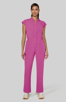 A pink jumpsuit with short sleeves and a front pocket, modelled by a woman against a grey background.