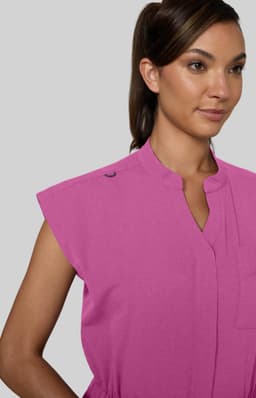 A pink jumpsuit with short sleeves and a high collar, featuring a logo on the shoulder.