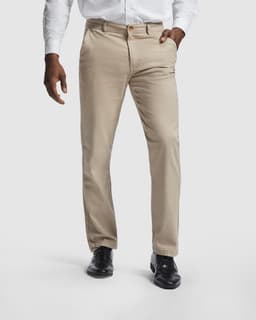 Beige trousers with a straight fit, featuring pockets and a logo, paired with a white shirt and black shoes.