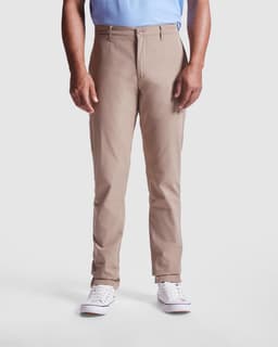 Beverly Chino Trousers in light beige, featuring a slim fit and front pockets. The model is wearing white sneakers.
