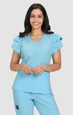 A blue medical top with ruffled sleeves, featuring a V-neck and a relaxed fit. The model is smiling.